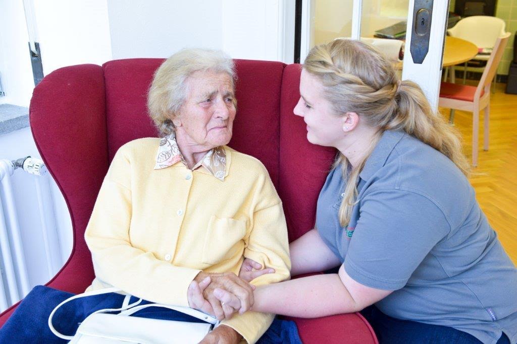 Pflegefachkraft kümmert sich liebevoll um Seniorin